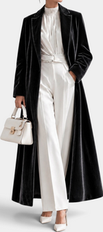 Mahaute long black velvet coat with elegant lapels, worn over a white blouse and trousers for a sophisticated look.