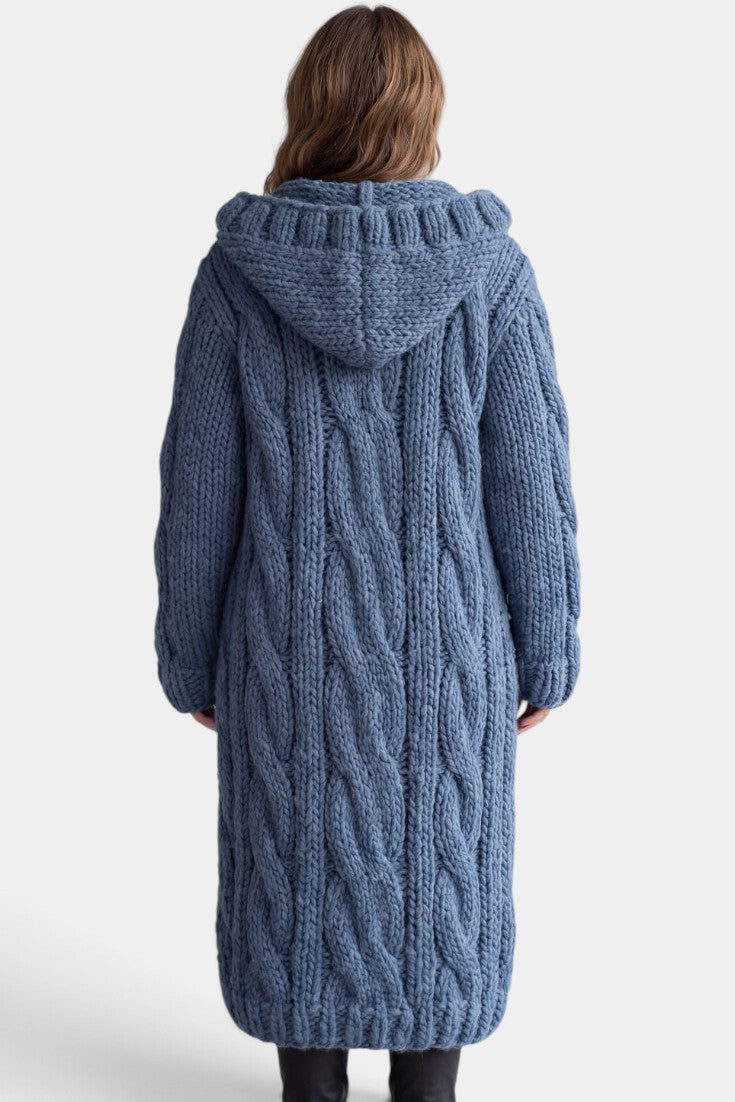 Cardigan long en maille torsadée bleu de Mahaute avec capuche et boutons, porté sur un modèle.