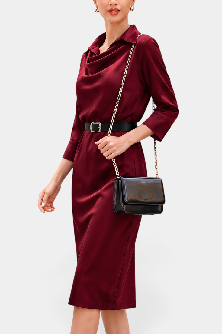 Mahaute Macarena midi dress in burgundy satin with a draped shirt collar, long sleeves, and a black buckled belt.
