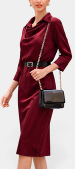 Mahaute Macarena midi dress in burgundy satin with a draped shirt collar, long sleeves, and a black buckled belt.