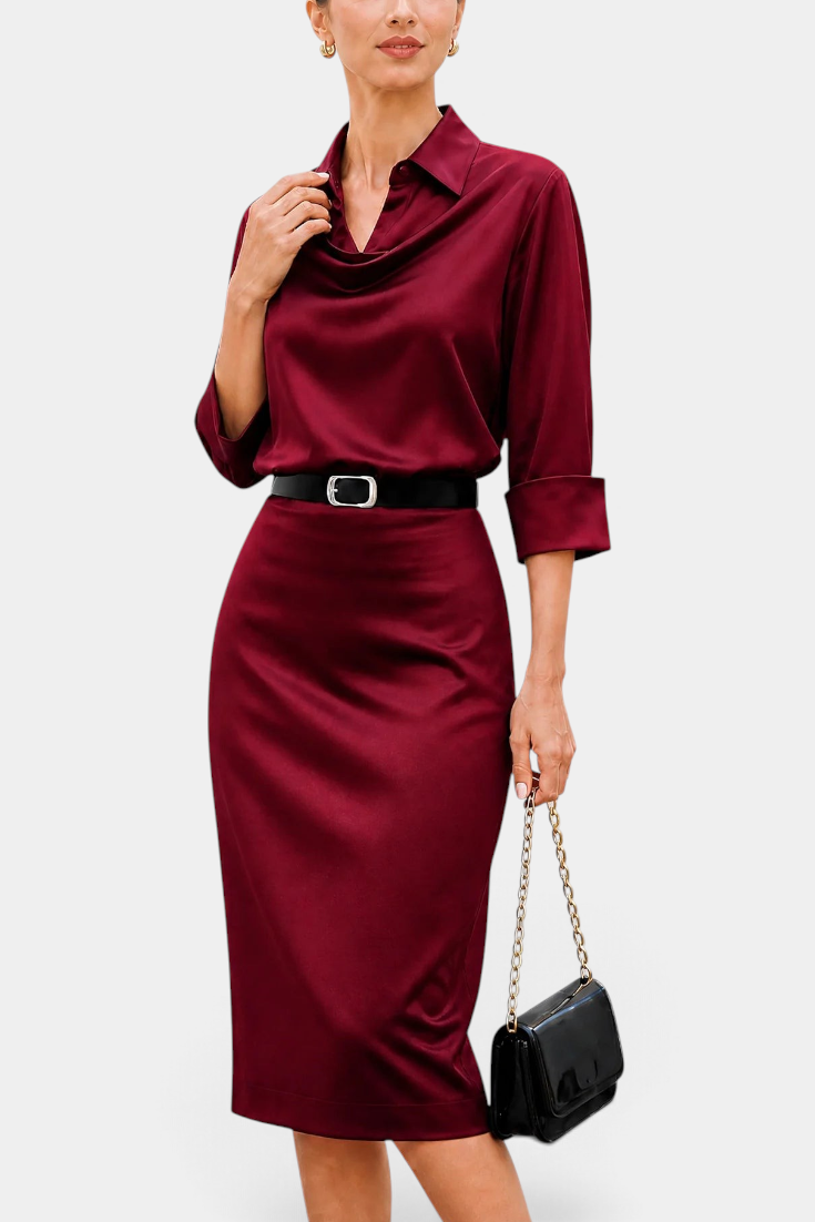 Mahaute Macarena midi dress in burgundy satin with a draped shirt collar, long sleeves, and a square buckle belt.