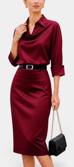 Mahaute Macarena midi dress in burgundy satin with a draped shirt collar, long sleeves, and a square buckle belt.