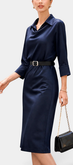 Mahaute Macarena midi dress in navy satin with a shirt collar, draped bodice, and a black belt with a square buckle.