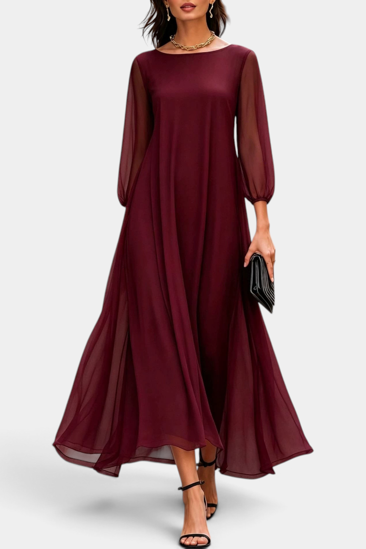 Mahaute Mazarine long burgundy flowing dress with sheer sleeves and flared skirt, worn with black heels on a city street.
