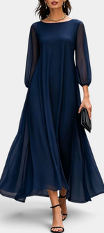 Mahaute Mazarine navy blue long flowing dress with sheer sleeves and flared skirt worn with black heels on a city street