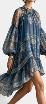Robe courte Mahaute Milagros en mousseline imprimée avec manches ballon, volants et design asymétrique, style floral bleu.
