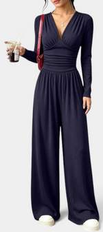 Mahaute Mirabel navy blue long-sleeve jumpsuit with V-neck, ruched bodice, and wide-leg trousers.