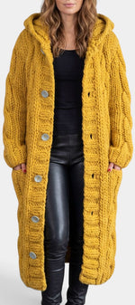 Cardigan long en maille torsadée Mahaute, à capuche et boutons, couleur moutarde, doux et chaud, porté ou posé à plat.