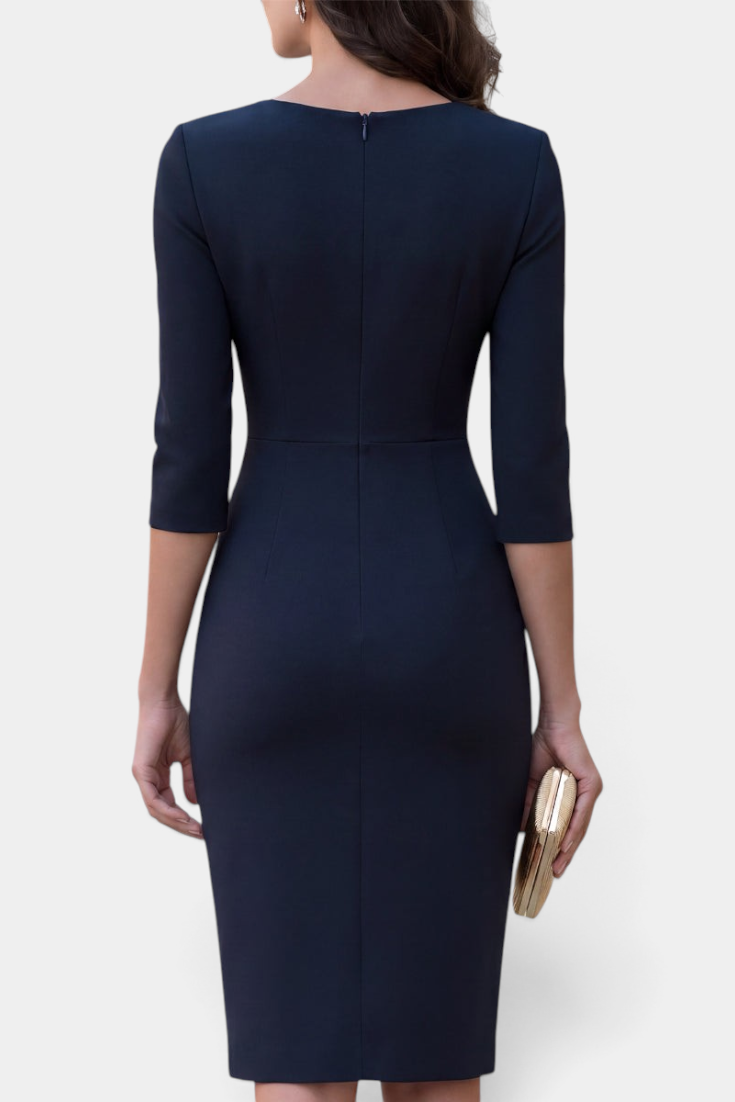 Back view of a Mahaute navy blue midi sheath dress with three-quarter sleeves, worn with a gold clutch