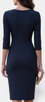Back view of a Mahaute navy blue midi sheath dress with three-quarter sleeves, worn with a gold clutch