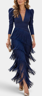 Mahaute navy blue long dress with layered fringe skirt, deep V-neckline, and structured puff sleeves on a model.