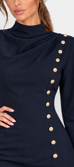 Mahaute navy blue short fitted dress with a draped high neckline, structured shoulders, and asymmetric gold buttons.