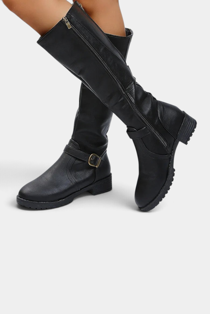 Mahaute Nevena black faux leather knee-high boots with a buckled ankle strap, side zipper, and chunky lug sole.
