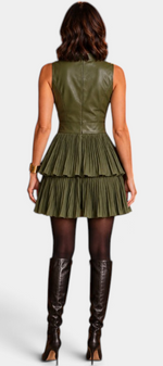 Back view of a woman wearing a Mahaute olive green sleeveless dress with a faux leather bodice and pleated skirt.