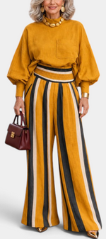 Mahaute Orlianne mustard blouse with puff sleeves and high-waisted wide-leg trousers featuring vertical stripes.