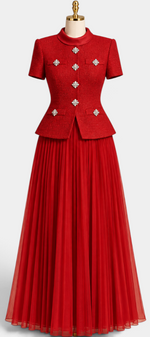 Mahaute red structured short-sleeve jacket with crystal jewel buttons paired with a long pleated skirt on a mannequin