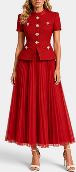 Mahaute red structured short-sleeve jacket with jewel buttons and matching pleated long skirt on a model