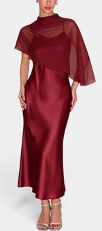 Mahaute midi satin dress in burgundy with a draped neckline and sheer asymmetric cape overlay for formal events.