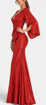 Mahaute red sequin evening gown with a wrap V-neck, flared sleeves, and a belted waist on a model, side view.