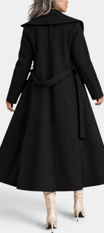 Mahaute Rony long black belted coat with an asymmetrical collar, worn with beige high-heeled boots, back view.