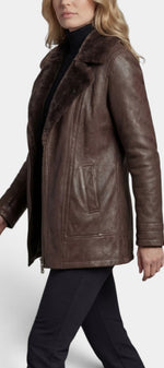 Veste mi-longue en faux cuir marron avec col fourré et fermeture zippée par Mahaute, vue de face.