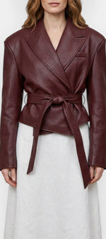 Veste courte en faux cuir rouge bourgogne Mahaute Rouxvelle avec ceinture et col tailleur, style élégant et moderne.