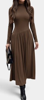 Robe longue marron Mahaute Sabea à col montant, manches longues et taille asymétrique, portée avec un style élégant et moderne.