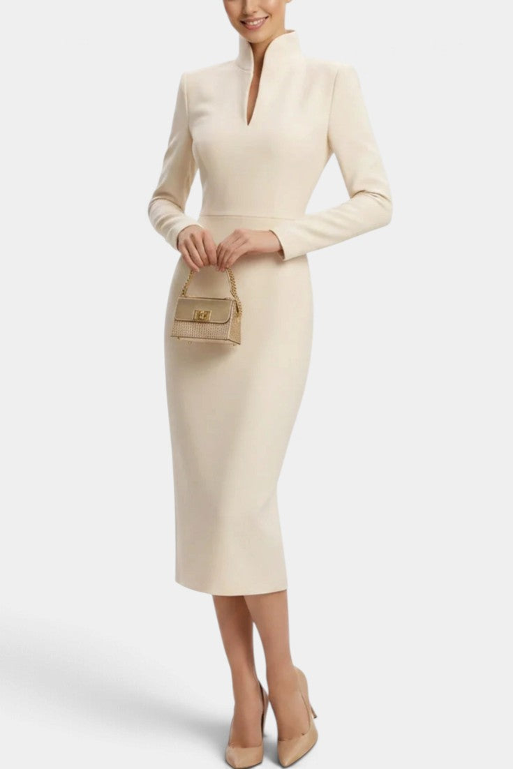 Mahaute Sandy cream midi dress with a high slit collar, long sleeves, and a fitted waist, styled with nude heels.