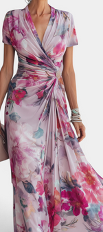 Mahaute Sanna long floral wrap dress with draped waist, jewel button detail, and watercolor print in pink and purple.