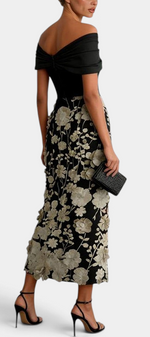 Mahaute Shay off-shoulder black maxi dress featuring a fitted bodice and a skirt with textured floral embroidery.