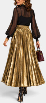Mahaute Tegan high-waisted gold metallic pleated maxi skirt worn with a black blouse and dark handbag