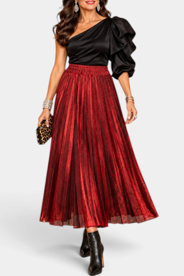 Mahaute Tegan high-waisted red metallic pleated midi skirt worn with a black one-shoulder top and black ankle boots.
