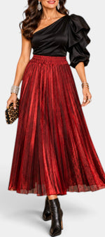 Mahaute Tegan high-waisted red metallic pleated midi skirt worn with a black one-shoulder top and black ankle boots.
