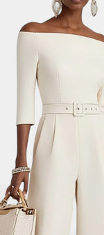 Mahaute Tisdale off-shoulder cream jumpsuit with three-quarter sleeves, belted waist, and wide-leg trousers.