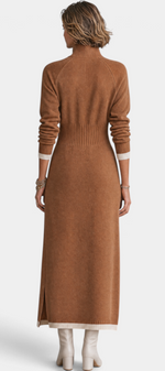 Back view of a Mahaute Tryphena long brown knit dress with a ribbed waist, zip collar, and side slit on a model.