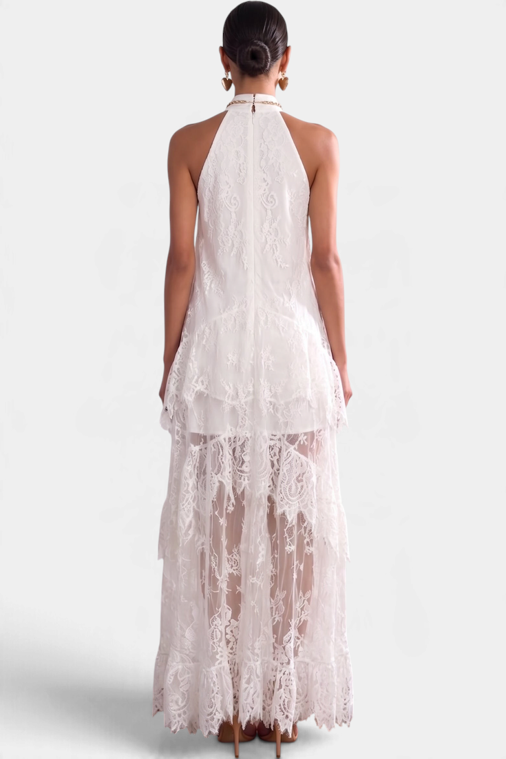 Back view of a model wearing a Mahaute white lace maxi dress with a high neck, ruffles, and sheer detailing.