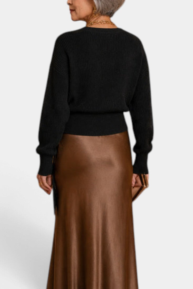 Mahaute Zia black ribbed knit sweater with long sleeves worn with a brown satin midi skirt, back view