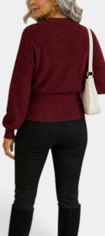 Back view of a woman wearing a Mahaute burgundy ribbed knit wrap sweater with long sleeves and a tied waist.