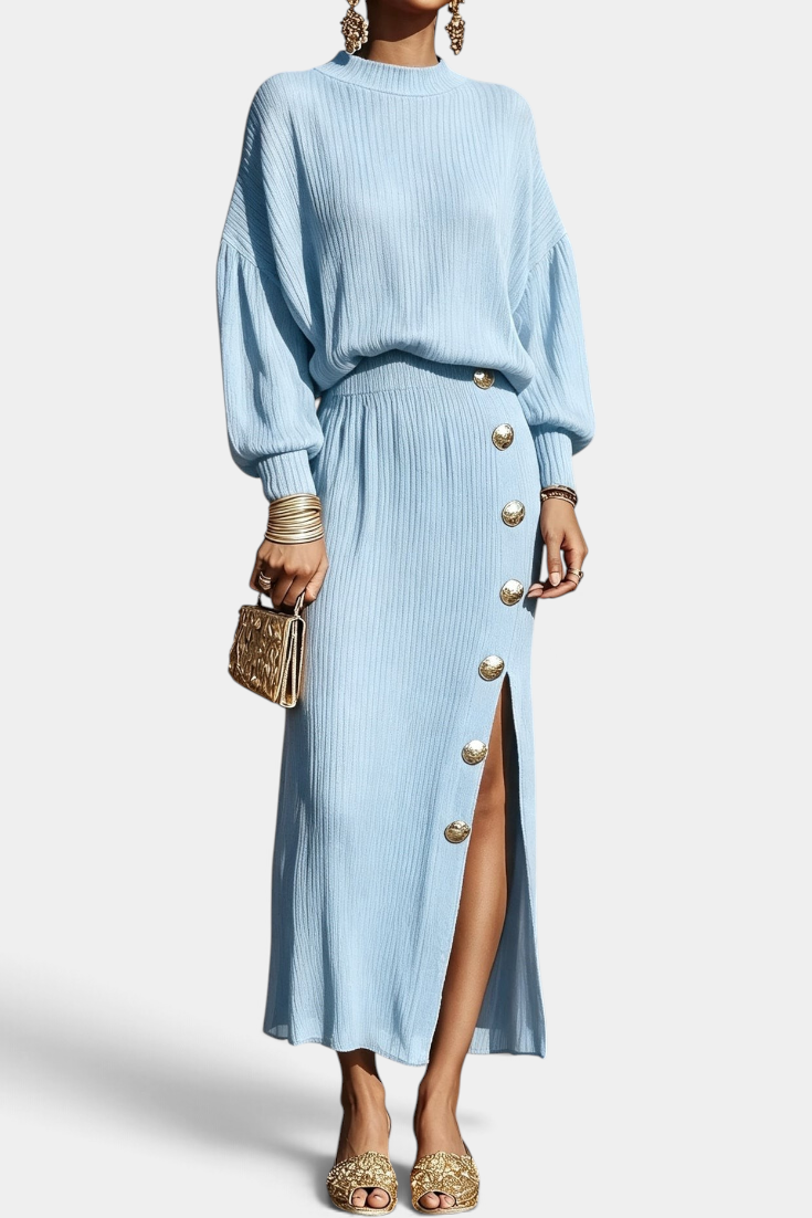 Mahaute Zornitsa light blue pleated two-piece set with a fluid blouse and a long skirt featuring gold button details.