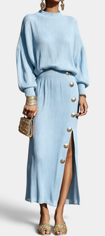 Mahaute Zornitsa light blue pleated two-piece set with a fluid blouse and a long skirt featuring gold button details.