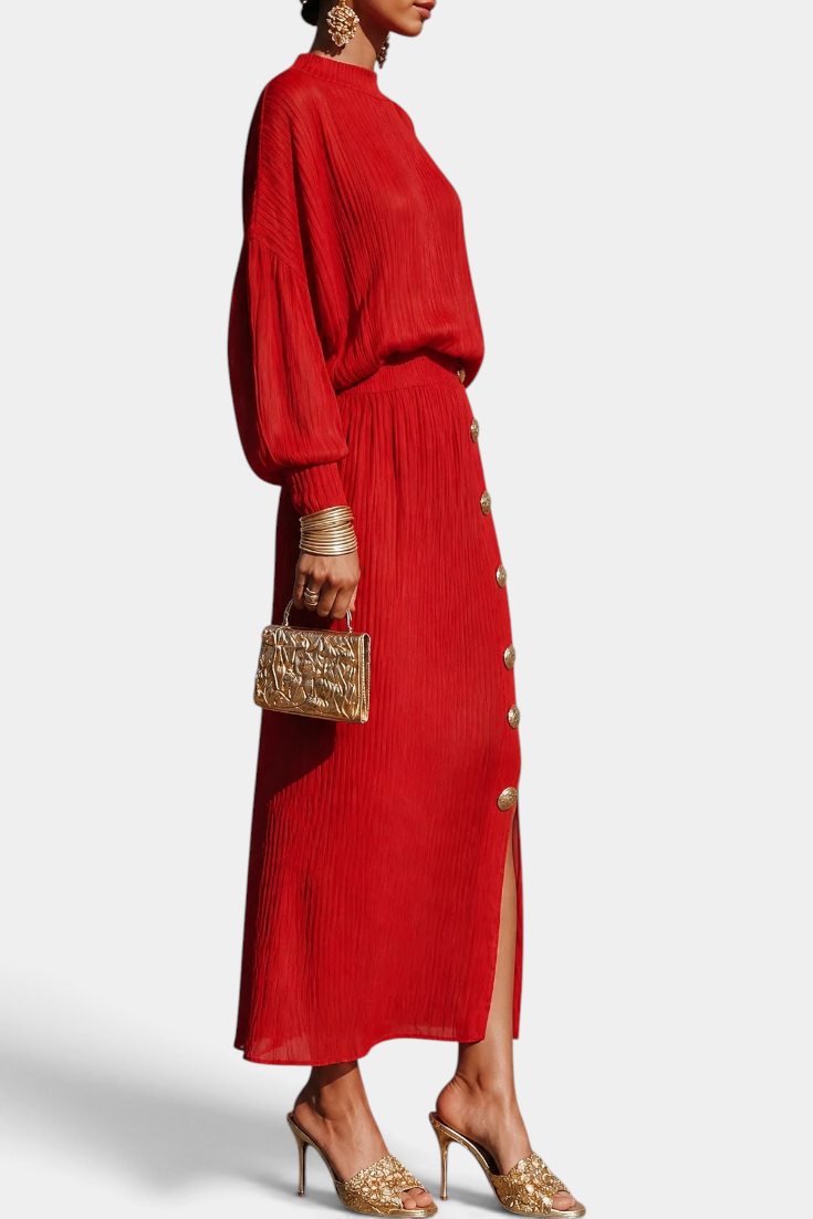 Mahaute red pleated two-piece set with a fluid blouse and long skirt featuring gold buttons and a side slit.